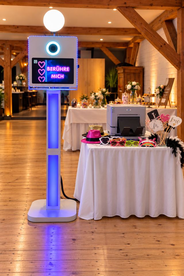 Fotobox mit blau leuchtender Säule und Requisitentisch in einer Eventlocation